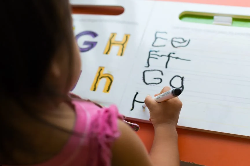 A child making marks and letters with a marker